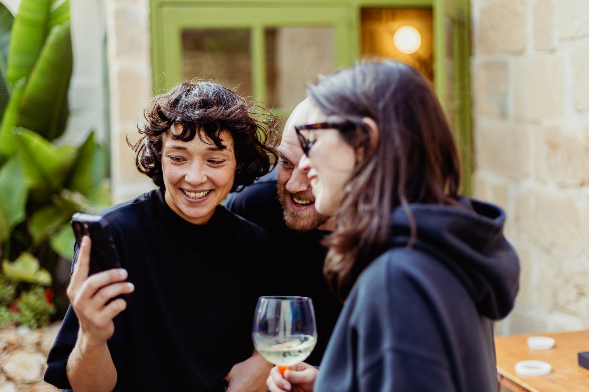Two people laughing over a glass of wine in the courtyard